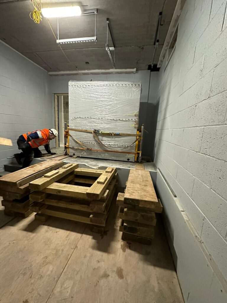 Appointed Person looking at a heavy object that is about to be moved on to a pallette of wood.